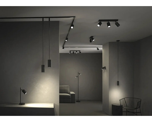 Modernt belysningssystem i ett rum med skenstrålkastare, pendellampor, golvlampa och bordslampa av svart metall i industriell stil.