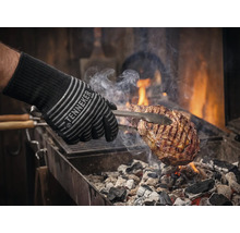 Grillhandske med kött på grillen