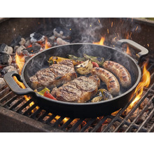 Grillpanna med biffar, korvar och grönsaker på grillen