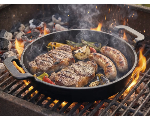 Grillpanna med biffar, korvar och grönsaker på grillen
