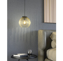 Scen med en gyllene hänglampa ovanför ett nattduksbord bredvid en säng.