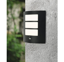 Svart vägglampa med rörelsedetektor och tre rektangulära ljusfönster på en vägg.