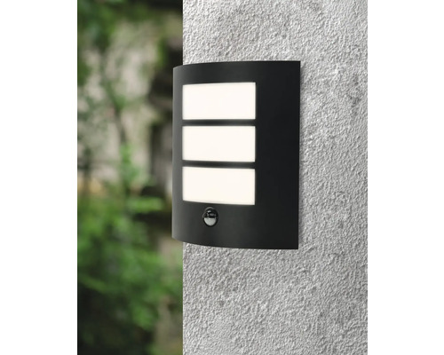 Svart vägglampa med rörelsedetektor och tre rektangulära ljusfönster på en vägg.