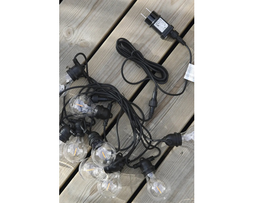 LED-ljusslinga med transparenta glödlampor och svart kabel på träplankor.