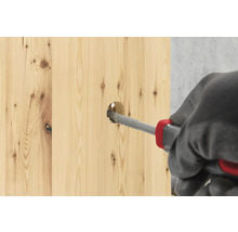 En träplanka bearbetas med en rasp.