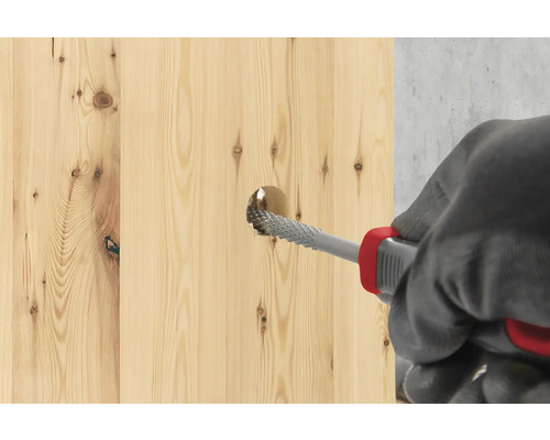 En träplanka bearbetas med en rasp.