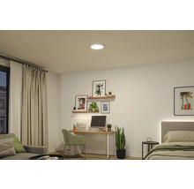 Rund LED-taklampa i ett ljust, modernt inrett rum med skrivbord, vägghyllor och säng.