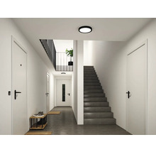 Modern hall med dörrar, trappa, skoställ och platt, rund taklampa.