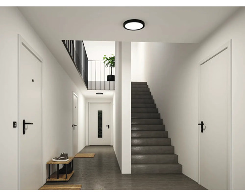 Modern hall med dörrar, trappa, skoställ och platt, rund taklampa.