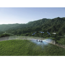 Robotgräsklippare på en brant grässluttning med satellitnavigering och virtuell begränsningskabel i ett bergslandskap.