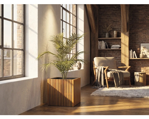 Kvadratisk blomlåda i träribbor med en krukväxt i ett ljust vardagsrum med tegelvägg och stora fönster.