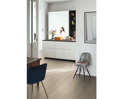 Modernt ljust rum med laminatgolv i ljust träutseende, en vit köksö med svart bänkskiva och designstolar.