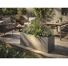 Stor rektangulär planteringslåda i betonglook på en träaltan i en modernt designad trädgård med sittgrupp och eldfat.