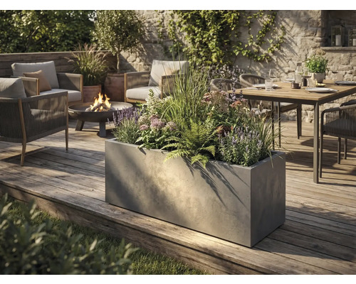 Stor rektangulär planteringslåda i betonglook på en träaltan i en modernt designad trädgård med sittgrupp och eldfat.