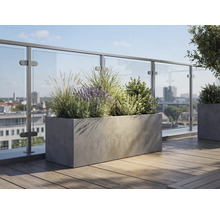 Rektangulär blomlåda i betonglook på en takterrass med trägolv och glasräcke, planterad med lavendel och prydnadsgräs.