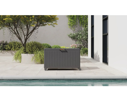 Grå dynbox med hjul och trähandtag på en modern terrass med pool och växter.