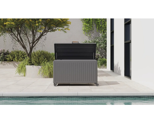 Modern förvaringsbox i metall för trädgården med öppet lock på en ljus terrass intill en pool.