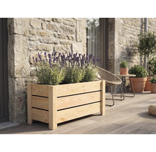 Rektangulär blomlåda i trä med ribbor fylld med blommande lavendel på en träterrass framför en stenvägg.