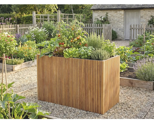 Hög odlingslåda av träribbor med tomater, sallad och örter i en ljus, organiserad trädgård med grusgångar.