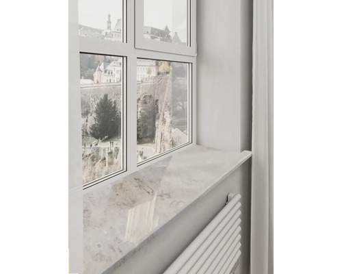 Ljus fönsterbänk i naturstenslook under en vit fönsterkarm med utsikt över historiska murar.