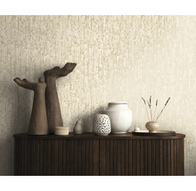 Strukturerad tapet med vertikalt mönster i beige bakom en mörk sideboard med dekorationsobjekt och skulpturer.
