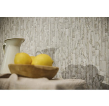 Non-woven tapet med abstrakt mönster av stenblock i ett ljust rum bakom en kanna och en träskål med citroner.
