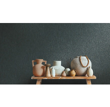 Mörkgrå non-woven tapet med vertikal struktur bakom ett urval av olika keramikvaser på en rustik träbänk.