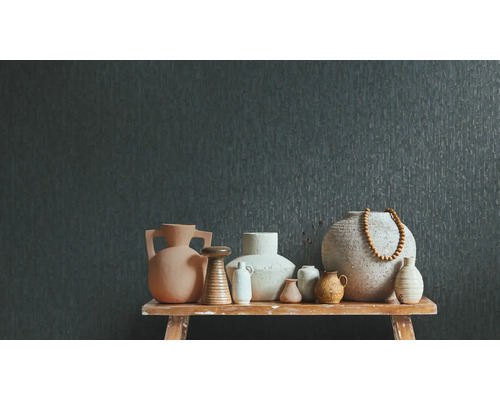 Mörkgrå non-woven tapet med vertikal struktur bakom ett urval av olika keramikvaser på en rustik träbänk.