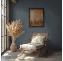 Rustikt rum med mönstrad vägg, trästol med rotting, vas med pampasgräs och inramad tavla i naturligt dagsljus.