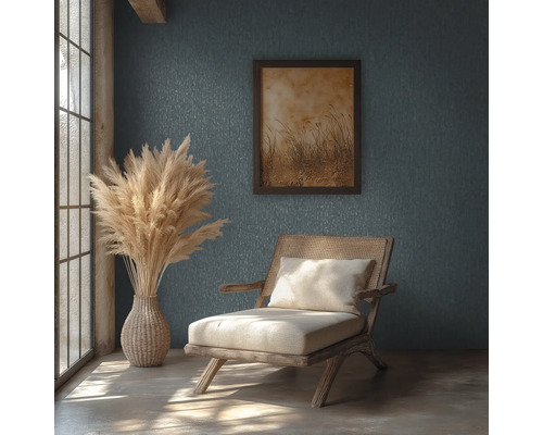 Rustikt rum med mönstrad vägg, trästol med rotting, vas med pampasgräs och inramad tavla i naturligt dagsljus.