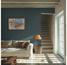 Ljust vardagsrum med mörkblå strukturtapet på väggen, vit soffa och solljus på trägolvet.