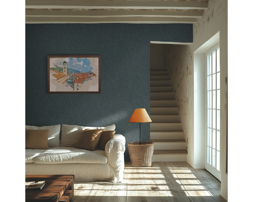 Ljust vardagsrum med mörkblå strukturtapet på väggen, vit soffa och solljus på trägolvet.