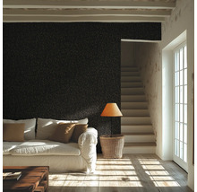 Vardagsrum med strukturerad väggtapet, soffa, träbord, golvlampa och trappa bredvid ett fönster.