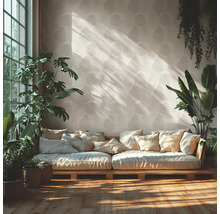 Ljust vardagsrum med tapet med bladmönster, en träsoffa med många kuddar och olika inomhusväxter på ett trägolv.