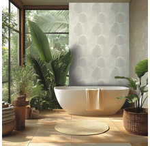 Ljust badrum med vitt fristående badkar, tapet med palmmönster, stora gröna växter och en rund naturfibermatta.