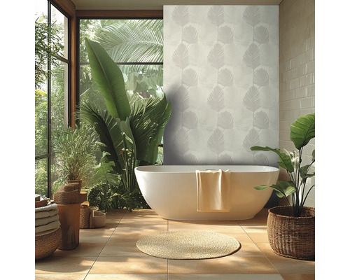 Ljust badrum med vitt fristående badkar, tapet med palmmönster, stora gröna växter och en rund naturfibermatta.