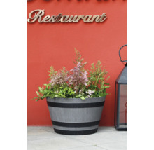 Planteringskärl i fatform med träådring och svarta ringar, planterad med rosa astilbe, placerad bredvid en svart lykta.