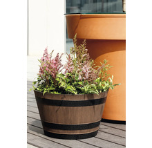 Blomkruka med trälook i form av ett träfat med mörka band, planterad med rosa astilbe på en träterrass.