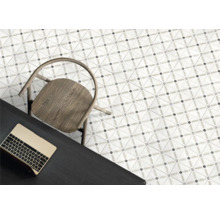 Moderna golvplattor med geometriskt mönster, trästol och mörkt skrivbord med bärbar dator i ett ljust rum.