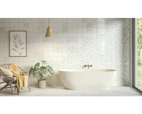 Ljust badrum med fristående badkar och kvadratiskt kakel med blommiga och enkla mönster.