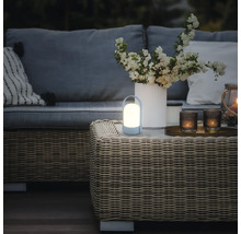 Bärbar LED-utomhuslampa på ett soffbord av konstrotting i en loungegrupp med soffa, blomvas och ljuslyktor.