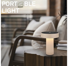 Bärbar LED-bordslampa med solpanel på ett sidobord i trä i en mysig utomhusmiljö på en terrass.
