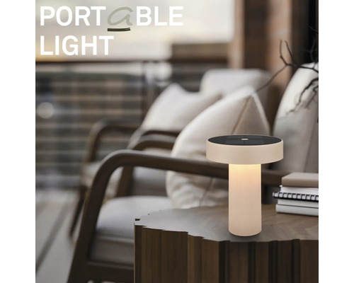 Bärbar LED-bordslampa med solpanel på ett sidobord i trä i en mysig utomhusmiljö på en terrass.