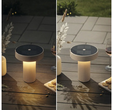 Modern solcellsdriven bordslampa med räfflad bas på ett trädgårdsbord, jämförelse i dagsljus och i skymning med varmt ljus.