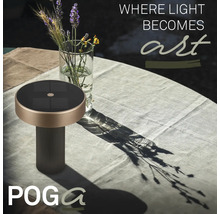 POGA solcellsbordslampa på ett trädgårdsbord med duk bredvid en glasvas med blommor.