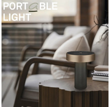 Modern bärbar bordslampa för utomhusbruk på ett sidobord i trä i en organiserad balkongmiljö med loungesstolar och kuddar.