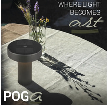 Solcellsdriven bordslampa på ett ljust, dukat trädgårdsbord med en blomvas och Poga Logo.