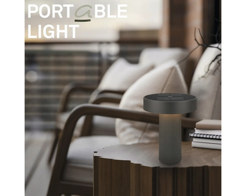 Modern bärbar LED-bordslampa på ett träbord på en uteplats med fåtöljer.