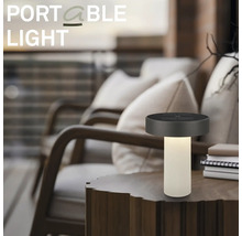 Bärbar LED-bordslampa på ett träbord i en modern utomhusmiljö med bekväma loungestolar.