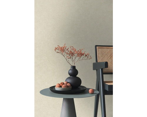 Strukturerad non-woven tapet i beige i ett modernt rum med sidobord, vas med torkade blommor och stol.